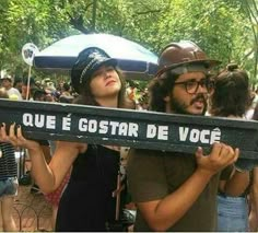 two people holding up a sign that says que e costar de voce in spanish