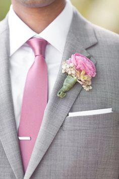 a man in a suit with a pink tie and flower boutonniere on his lapel