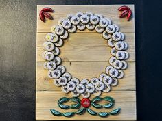 a wreath made out of buttons sitting on top of a wooden board