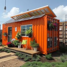 an orange shipping container with plants on the porch