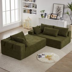 a living room with a large green couch and white rugs on the floor in front of a window