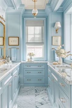 a bathroom with blue walls and marble counter tops, gold trim around the window sill