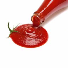 a bottle of ketchup being poured on to a red liquid with a green leaf