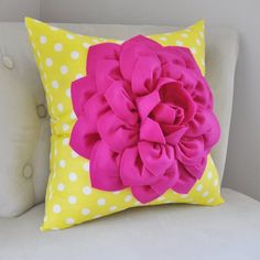 a yellow and white couch with a pink flower on the back of it's pillow