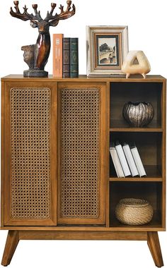 a wooden cabinet with wicker doors and two deer heads on the top shelf next to books