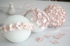 three white vases with flowers on them sitting on a table next to confetti