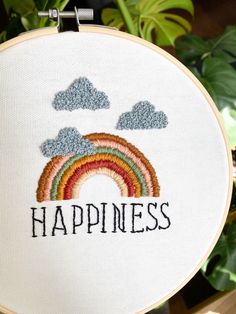 a cross stitch pattern with the words happiness and a rainbow in front of some clouds