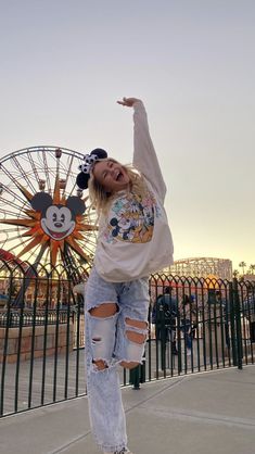 a girl in ripped jeans and a mickey mouse shirt doing a trick on a skateboard