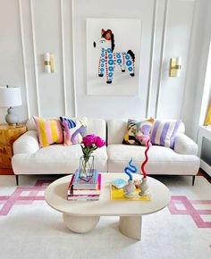 a living room filled with white furniture and colorful pillows