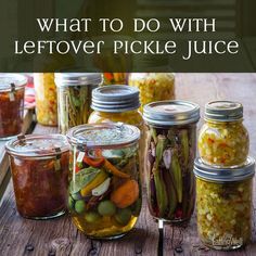 jars filled with pickles and vegetables sitting on top of a wooden table next to each other