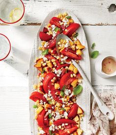 a white platter filled with tomatoes, corn and feta cheese