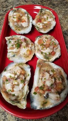 six oysters on a red platter with garnishes and seasoning