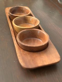 three wooden bowls are lined up in a row on a table with one empty bowl