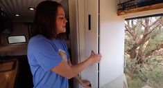 a woman standing in front of a window holding onto the handle of a sliding glass door