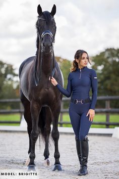 a woman standing next to a brown horse