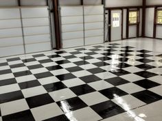 an empty garage with black and white checkered flooring in the center, two doors open