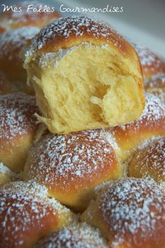 powdered sugar covered donuts sitting on top of a white plate