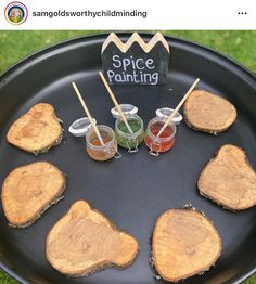 there are several slices of wood on the grill with dipping sauces in them and two small cups