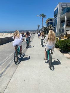 several people riding bikes on the sidewalk by the beach