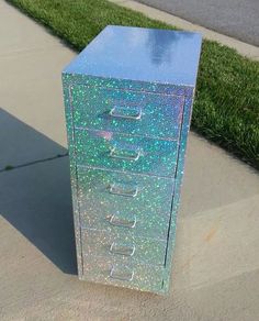 a metal filing cabinet sitting on the side of a sidewalk next to some green grass