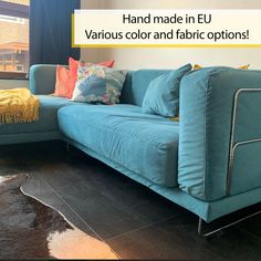 a blue couch sitting in front of a window next to a cowhide rug on top of a hard wood floor