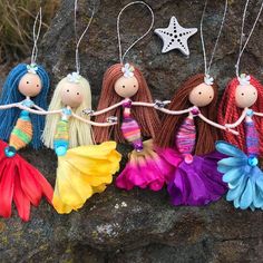 four little dolls hanging from strings on a rock