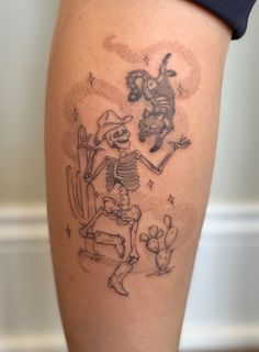 a person with a skeleton tattoo on their leg and some cacti in the background