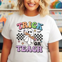 Get ready to add a playful twist to your classroom attire with our "Trick or Teach" Halloween Teacher Shirt! Featuring a charming ghost holding a pencil, this funny and cute teacher tee is perfect for educators who love to embrace the spooky spirit of Halloween. Details: - High-Quality Material: Made from soft, breathable cotton blend, ensuring comfort throughout the day. - Unique Design: Adorable ghost and pencil graphic with vibrant colors and playful text, making it a standout piece. - Versat White T-shirt For School In Fall, Holding A Pencil, Link Halloween, Halloween Teacher Gifts, Autumn Hair Accessories, Cute And Spooky, Pencil Design, Halloween Treat Bags, Funny Ghost