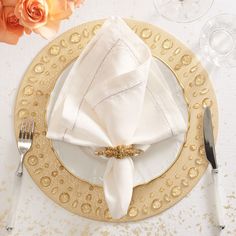 a place setting with napkins, silverware and flowers on a table cloth covered plate