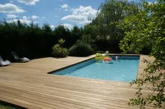 a wooden deck next to a pool with an inflatable floater on it