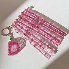 a pink heart shaped keychain sitting on top of a white table next to a pair of scissors