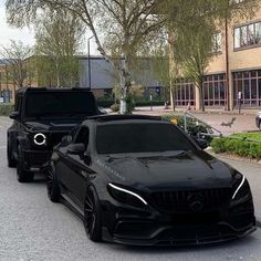 two black mercedess parked on the street next to each other