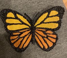 a yellow and black butterfly sitting on top of a gray shirt