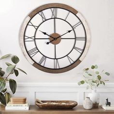 a large clock mounted to the side of a wall next to a potted plant