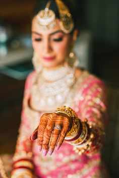 a woman in a pink and gold bridal outfit holding out her hand