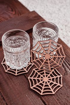 two glasses sitting next to each other on top of a wooden table covered in spider webs