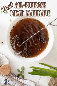 a bowl filled with meat marinade next to two spoons