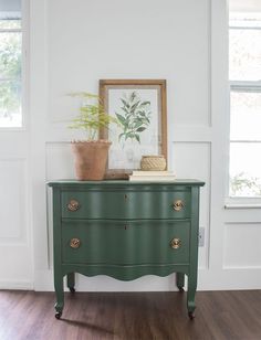 a green dresser in a white room with a potted plant on top of it