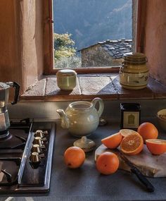 there are oranges on the counter next to an open window with mountains in the background