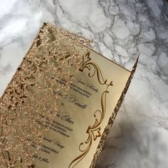 the inside of a wedding card with gold glitters on it sitting on a marble surface