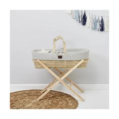 a wicker baby bassinet on a rug in front of a white wall