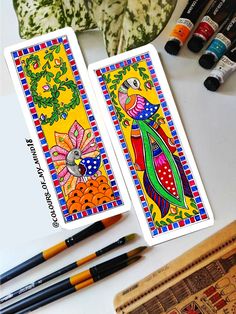 two playing cards sitting on top of a table next to some markers and pencils