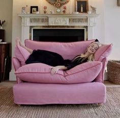 a woman laying on top of a pink couch