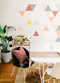 a dining room table with two chairs and a rug in front of the wall that has triangles on it