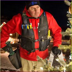 a man standing in front of a christmas tree holding two ski poles and an umbrella