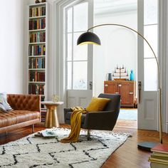 a living room filled with lots of furniture and bookshelves next to a window