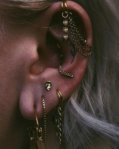 a woman wearing gold ear piercings and chains