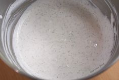 a bowl filled with white liquid sitting on top of a wooden table