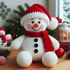 a crocheted snowman sitting on top of a table next to christmas decorations