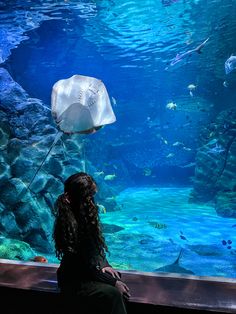 a girl looking at fish in an aquarium with a plastic bag on her head,